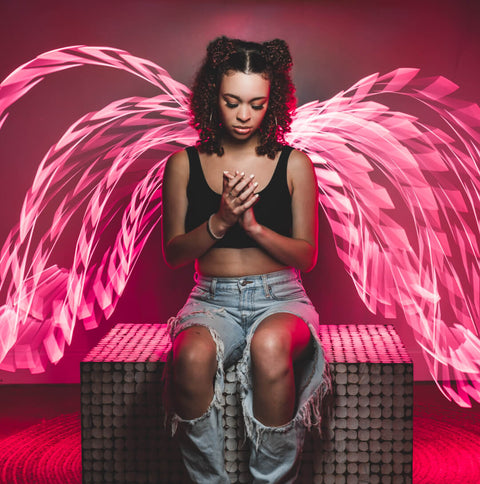 Pink light painting wings traced around a seated model
