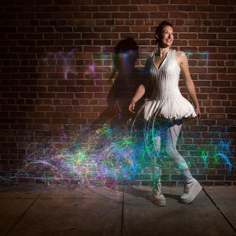 Performer in a white dress with fiber optic light trails created by the costume accessory