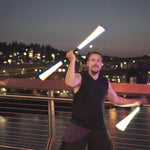 Flow artist performing at a festival while spinning two RGB Critter BT light staffs for a dynamic flow arts show