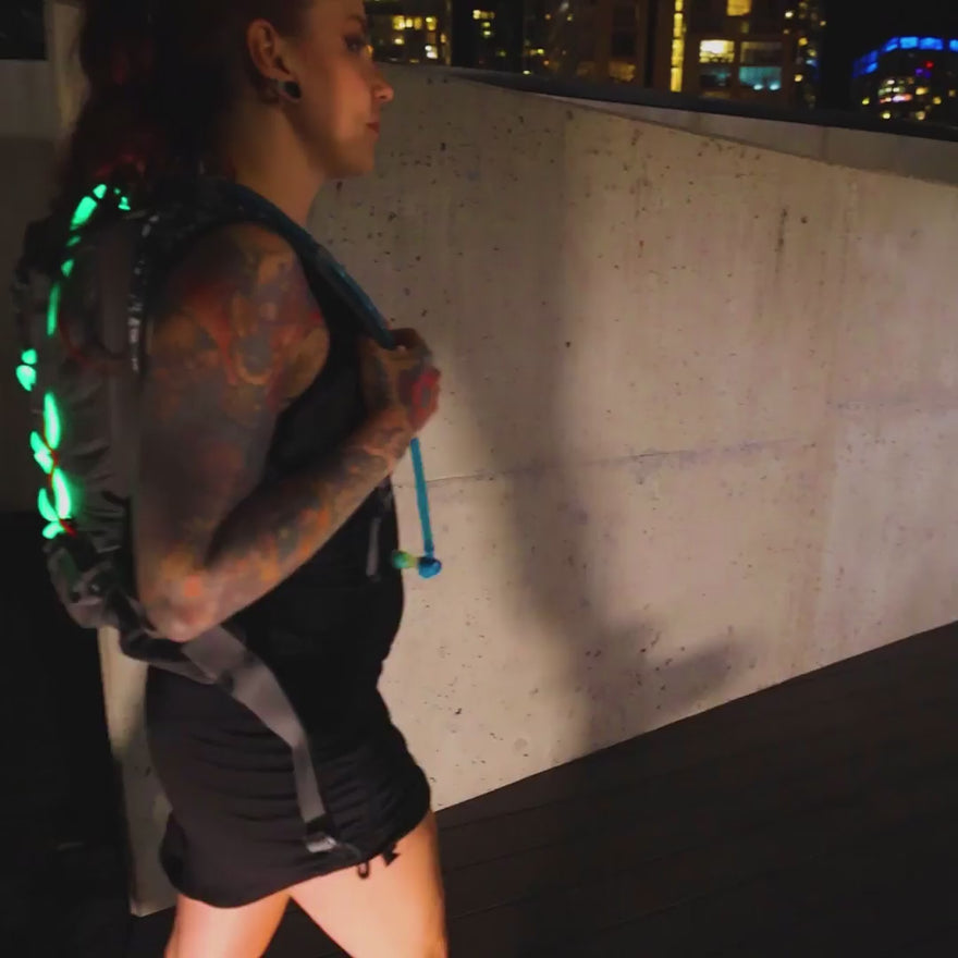 RGB Jupiter Jump Rope woven into a backpack and connected to an RGB Critter BT flashlight, creating a glowing, wearable light display for festivals like Burning Man and flow art performances.