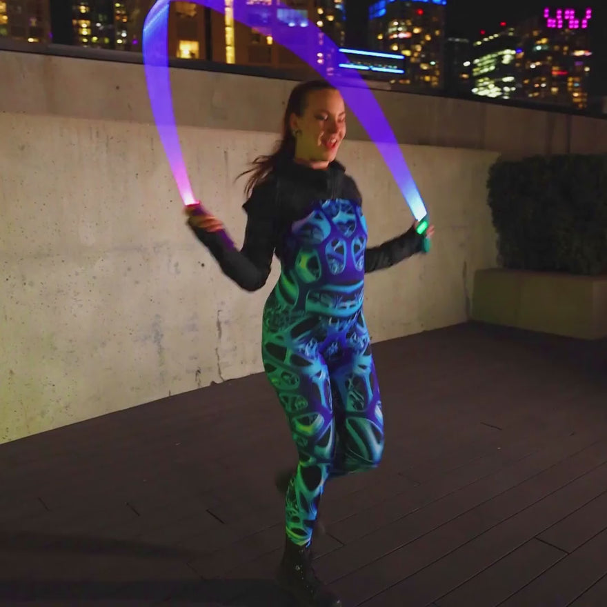 Video of a woman spinning RGB Jupiter Jump Rope accessory powered by RGB Critter BT flashlights, creating vibrant light trails for flow arts and festival performances.
