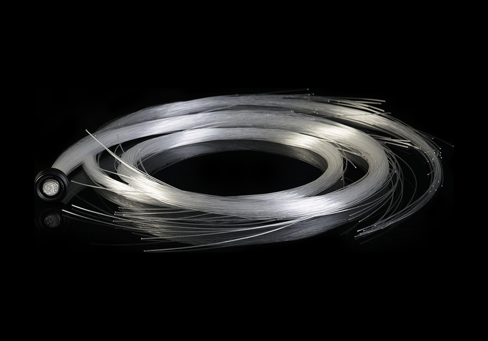 Bare BitWhip fiber optic bundle coiled on black, showing the individual unlit fiber strands
