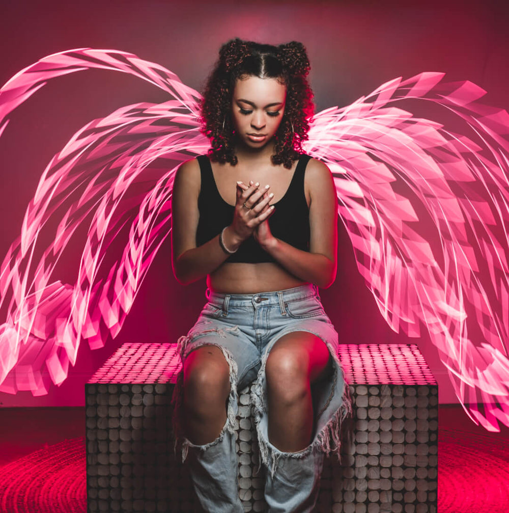 Pink light painting wings traced around a seated model