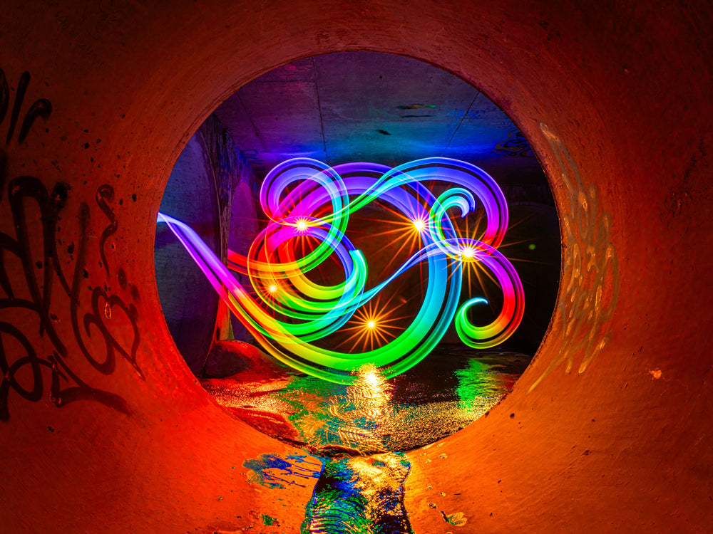 Rainbow light painting swirls inside a graffiti tunnel