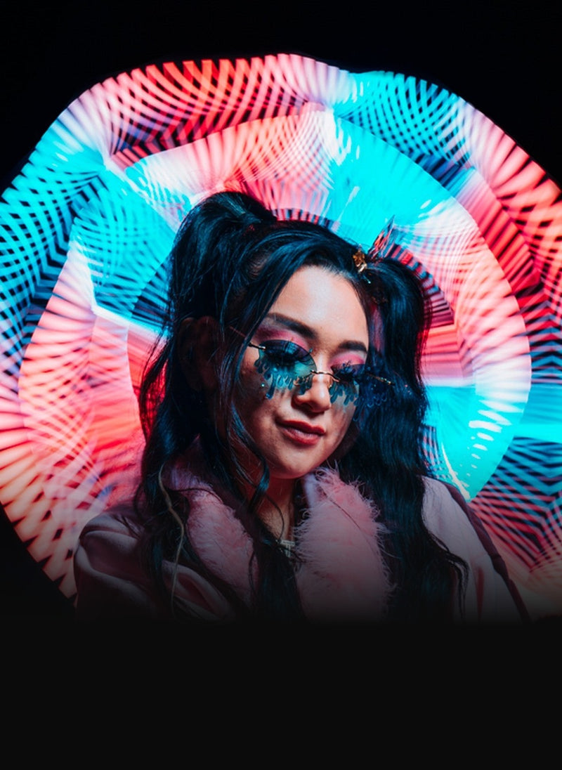 Flow artist framed by a real fiber optic whip spun into a full circle of pink and cyan light