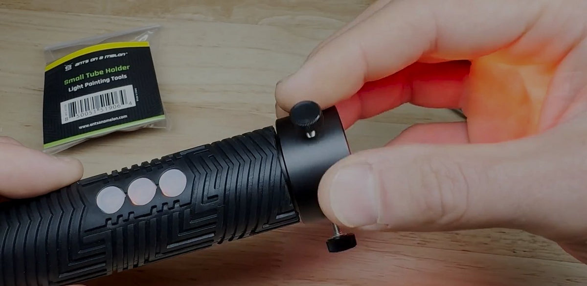 Hand twisting an accessory onto an RGB Critter flashlight