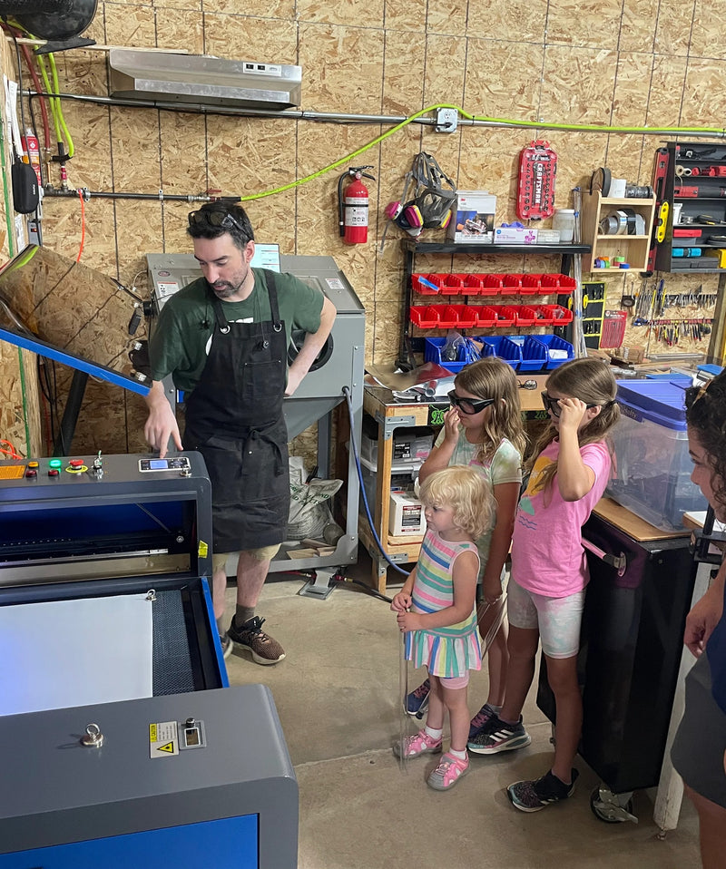 Laser cutter running in the Ants on a Melon workshop while children watch