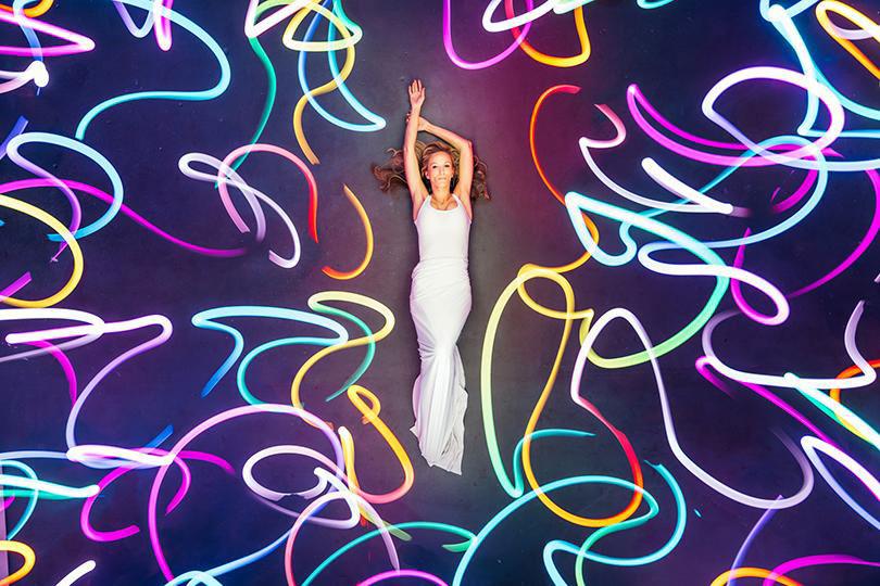 Light painting by Russell Klimas: a woman in white lying among looping RGB Critter light trails