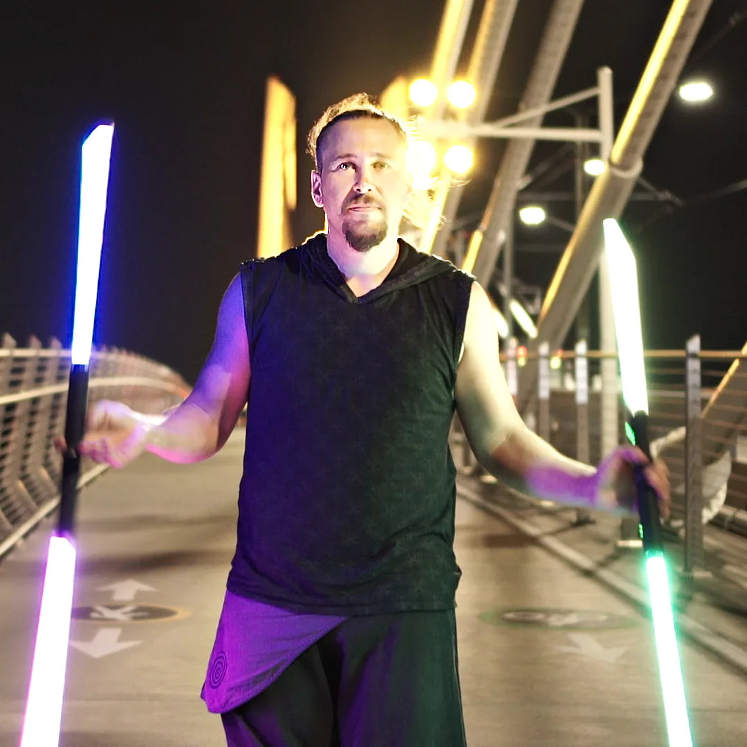 Tyler Spades holding two lit LED Staffs on Tilikum Crossing in Portland at night